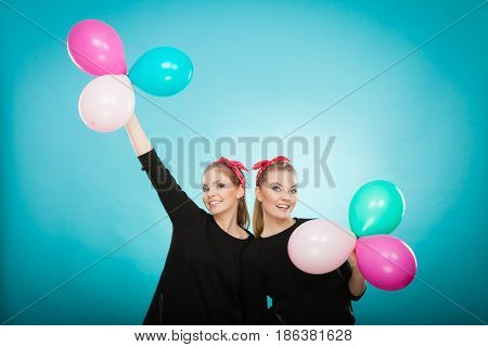 Memory of childhood and forgotten dreams. Two cute lovely retro styled women behave like little girls. Adults trying to fly away by balloons to dream come true.
