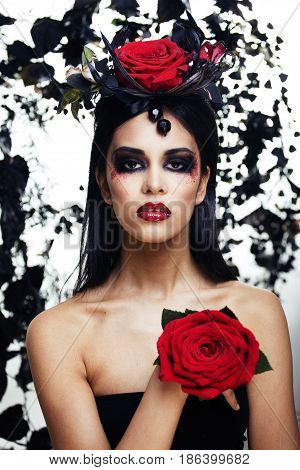 pretty brunette woman with rose jewelry, black and red, bright make up kike a vampire closeup red lips, halloween concept