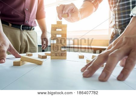 Hand Of Engineer Playing A Blocks Wood Tower Game (jenga) On Blueprint Or Architectural Project.