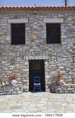 blue chair in front of typical greek house in agios dimitrios on the coast of messenia in mani part of peloponnese on sunny day in spring