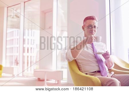 Mature businessman having coffee at office lobby