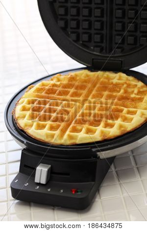 preparing homemade waffles by waffle maker machine.
