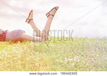 Low section of woman lying on grass against sky