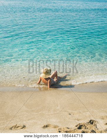 Beautiful slim senior woman tourist in bikini and hat lying on sand enjoying clear sea waters at Meditteranean resort of Turkey in Alanya, Kleopatra beach