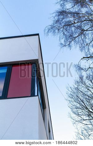 Red and white rendered modern building facade on a bright sunny day with clear sky. Abstract background.