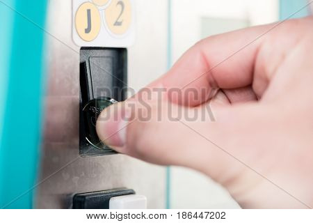 Close-up of male hand using coin-operated machine at self-service car wash