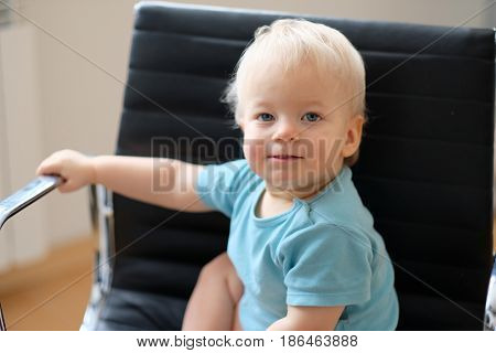 Baby boy with blue eyes indoor portrait. Toddler child sitting in chair