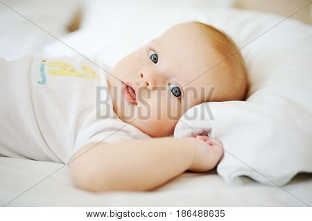 Portrait of a young child in white clothes against the background of a baby crib
