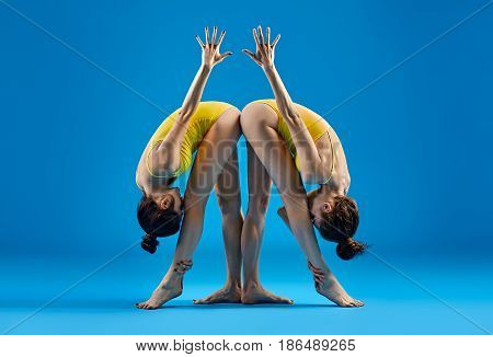 Two Young Women Doing Yoga Asana Standing Parsvottanasana