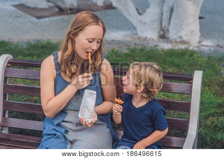 Mom And Son Eat Fried Sweet Potatoes In The Park. Junk Food Concept