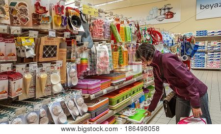 Eskisehir Turkey - April 17 2017: Kitchen utensils for sale on supermarket shelves in Eskisehir Turkey. Young woman shopping in kitchen utensils section in shopping mall.