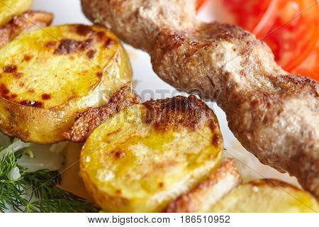 Grilled barbecue Lula Kebab with minced meat potatoes fresh vegetables and greens