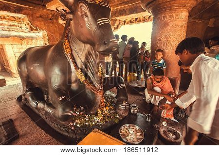 PATTADAKAL, INDIA - FEB 9, 2017: Brahman conducting a puja ritual inside the temple with the diety bull Nandi on February 9, 2017. UNESCO World Heritage site with stone carved structures of 7th-century