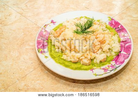 Plate with prawns and shrimps risotto on spinach bed