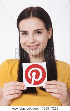 KIEV, UKRAINE - AUGUST 22, 2016: Woman hands holding Pinterest icon printed paper close up. Is photo sharing website.