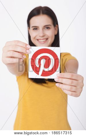KIEV, UKRAINE - AUGUST 22, 2016: Woman hands holding Pinterest icon printed paper close up. Is photo sharing website.