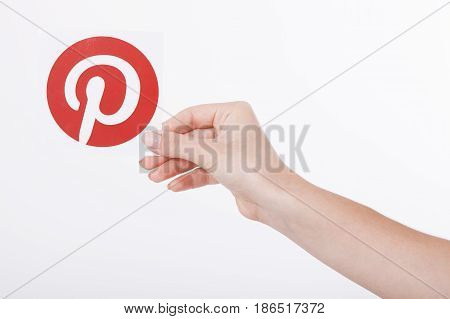 KIEV, UKRAINE - AUGUST 22, 2016: Woman hands holding Pinterest icon printed paper close up. Is photo sharing website.