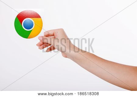 Kiev, Ukraine - August 22, 2016: Woman hands holding colorful Google Chrome icon printed on paper on grey background.Google is USA multinational corporation.