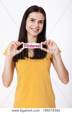 KIEV, UKRAINE - AUGUST 22, 2016: Woman hands holding Pinterest ilogotype icon printed paper close up. Is photo sharing website.