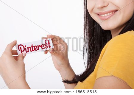 KIEV, UKRAINE - AUGUST 22, 2016: Woman hands holding Pinterest ilogotype icon printed paper close up. Is photo sharing website.
