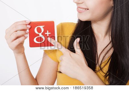 Kiev, Ukraine - August 22, 2016: Woman hands holding colorful Google plus icon printed on paper on grey background.Google is USA multinational corporation.