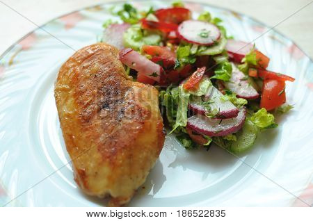 Baked Chicken Breast With Vegetable Salad On A White Plate
