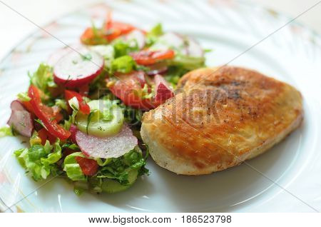 Baked Chicken Breast With Vegetable Salad On A White Plate