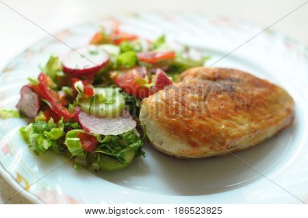 Baked Chicken Breast With Vegetable Salad On A White Plate
