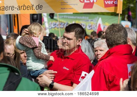 BERLIN - MAY 01 2016: A man with a child in her arms. Members of trade unions workers and employees at the demonstration on the occasion of Labour day.