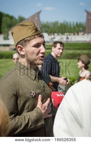 BERLIN - MAY 08 2016: Victory in Europe Day. Soviet War Memorial in Treptower Park. Journalist Ukrainian TV station 1+1 is interviewing a young man dressed in the form of a Soviet soldier during the war.