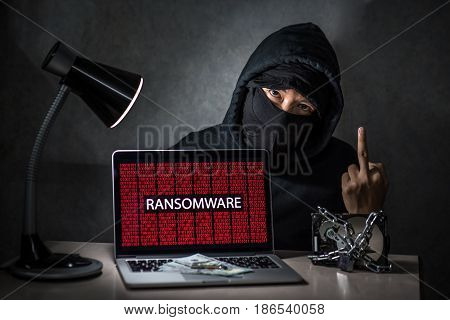 Hacker with computer screen showing ransomware attacking, alert in red digital binary background with hard disk drive lock. Cyber attack concept