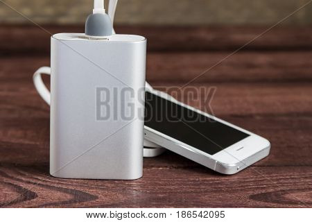Charging Smartphone With Portable External Battery ( Powerbank ) On A Wooden Background
