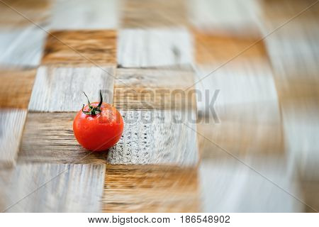 One organic ripe red tomat on surface mosaik board with pieces of different breeds as chess board background. Selective focus. Healthy eating concept, antioxidant and diet