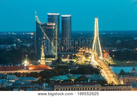 Riga, Latvia - July 2, 2016: Aerial View Of Cityscape In Evening Night Lights Illumination. Castle, President Residence, Swedbank Headquarters, Building Complex Z-towers, Vansu Cable-stayed Bridge