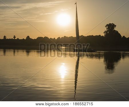 Traditional egyptian felluca sailing boat on river Nile in silhouette at dusk sunset