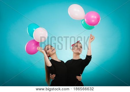 Memory of childhood and forgotten dreams. Two cute lovely retro styled women behave like little girls. Adults trying to fly away by balloons to dream come true.