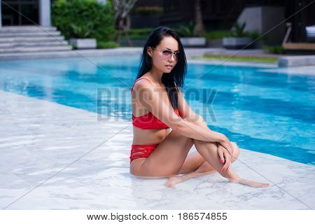 Close up lifestyle portrait of Cute girl swimming in pool, traveling and enjoy her summer vacation, perfect skin, trendy sunglasses. Outdoors lifestyle portrait