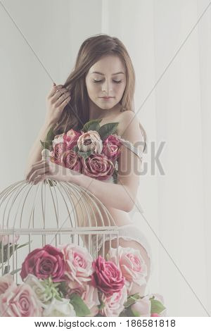 Lovely girl in underwear straightens hair. Bra of flowers. Spring mood. Soft focus.