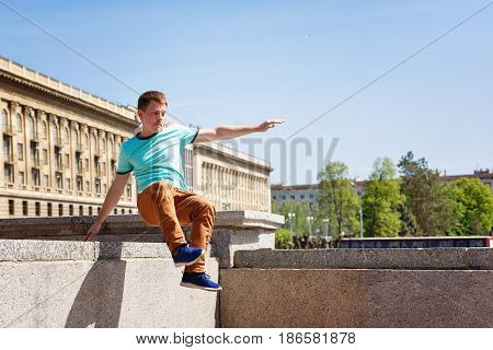 The young man jumps over the wall. Parkour in the urban space. Sport in the city. Sport activity.