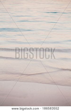 Closeup macro shot of sea ocean wave water with white foam sandy beach background with copyspace. Toned with retro vintage film effect style filters pastel faded colors