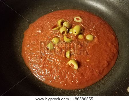 red speghetti sauce in black frying pan with olives
