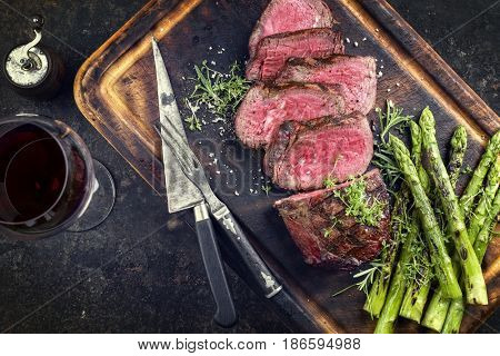 Barbecue Wagyu Point Steak with green Asparagus as close-up on burnt cutting board 