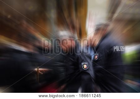 German police officers in action focus on the POLIZEI emblem on the uniform blurred crowd and surrounding background with zoom effect copy space
