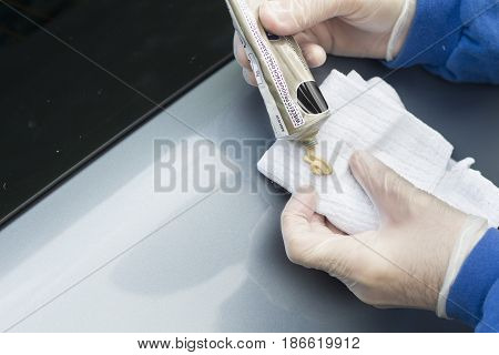 The hands of a man apply polishing paste on a white cloth.