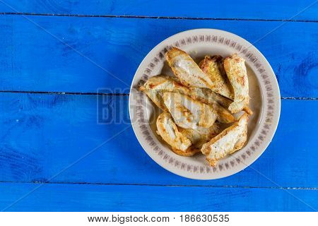 Flat lay above fried chicken breasts on the plate above blue wooden planks board.