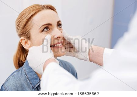 Positive mood. Delighted pleasant nice woman looking at her doctor and smiling while being in a positive mood