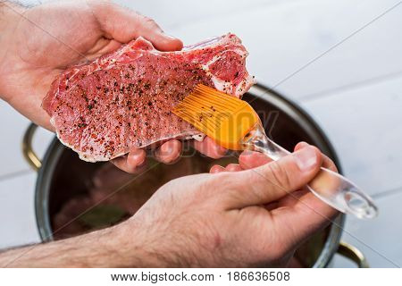 Close up of chefs hands spicing the meat. Casserole with raw meat on a white background.