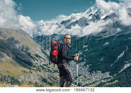 hiker on the trail in the Apls mountains. Trek near Matterhorn mount. Mountain ridge and Zermatt town on the background