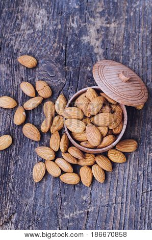 Tasty almonds nuts in wooden bowl on the old background with place for text. Healthy edible seeds food ingredient on the table. Top view. Copy space.