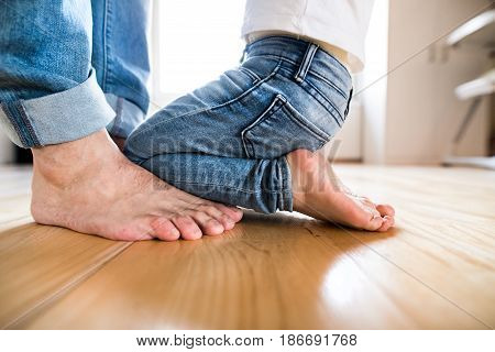 Beautiful young family. Close up of little girl kneeling at the bare feet of her father.